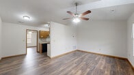 This 2-bedroom, 1-bathroom single-story home offers a practical and comfortable layout with consistent light-toned hardwood-style flooring and neutral walls throughout. The open-concept living, dining, and kitchen area forms the heart of the home, highlighted by a vaulted ceiling with a ceiling fan that enhances the sense of spaciousness and airflow. The kitchen features a galley-style design with warm honey-toned cabinetry lining both sides, light countertops, a double sink, and black appliances including a refrigerator, dishwasher, and range. A pantry door at the end of the kitchen provides convenient additional storage. Both bedrooms are well-proportioned, each equipped with a ceiling fan and a window that allows natural light to filter in. The primary bedroom is notably spacious, with room for a full furniture arrangement. The full bathroom includes a soaking tub-shower combination with a clean, bright surround. Additional functional spaces include a dedicated laundry area, a hallway connecting the rooms, and two closets for ample storage. The home's clean, move-in-ready condition and cohesive design make it a practical and inviting living space.