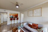 Located in Baton Rouge, Louisiana, this 2-bedroom, 1-bathroom residence offers a thoughtfully designed single-story layout that maximizes comfort and functionality. Wood-style flooring flows consistently throughout the home, unifying each space with a warm, cohesive aesthetic. Crown molding accents the main living areas, adding a refined architectural touch.

The living room is bright and welcoming, featuring a ceiling fan, large windows with exterior door access, and an open sightline to the kitchen. The kitchen is equipped with rich wood cabinetry, granite-style countertops, black appliances, and a peninsula with bar seating — ideal for casual dining. A pendant light above the sink adds a decorative focal point.

The primary bedroom is generously sized, offering ample natural light through large windows, a ceiling fan, and access to a dedicated walk-in closet. The second bedroom is equally comfortable, also featuring a ceiling fan and good natural light. The shared bathroom includes a dual-sink vanity with wood cabinetry, a soaking tub, and a separate shower area with clean, neutral finishes.

Two hallways connect the layout efficiently, and two closets — including a spacious walk-in — provide substantial storage. The overall palette of soft neutrals and warm wood tones creates a calm, livable atmosphere throughout.