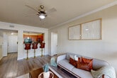 Located in Baton Rouge, Louisiana, this 2-bedroom, 1-bathroom residence offers a thoughtfully designed single-story layout that maximizes comfort and functionality. Wood-style flooring flows consistently throughout the home, unifying each space with a warm, cohesive aesthetic. Crown molding accents the main living areas, adding a refined architectural touch.

The living room is bright and welcoming, featuring a ceiling fan, large windows with exterior door access, and an open sightline to the kitchen. The kitchen is equipped with rich wood cabinetry, granite-style countertops, black appliances, and a peninsula with bar seating — ideal for casual dining. A pendant light above the sink adds a decorative focal point.

The primary bedroom is generously sized, offering ample natural light through large windows, a ceiling fan, and access to a dedicated walk-in closet. The second bedroom is equally comfortable, also featuring a ceiling fan and good natural light. The shared bathroom includes a dual-sink vanity with wood cabinetry, a soaking tub, and a separate shower area with clean, neutral finishes.

Two hallways connect the layout efficiently, and two closets — including a spacious walk-in — provide substantial storage. The overall palette of soft neutrals and warm wood tones creates a calm, livable atmosphere throughout.