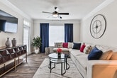 Located at 100 Parkway Cir S in Atlanta, Georgia, this single-floor residence offers a well-appointed layout with consistent warm-toned walls and rich hardwood-style flooring that flow seamlessly throughout every room. The living room is a welcoming focal point, featuring crown molding, a ceiling fan, large windows dressed in navy curtains, and a comfortable sectional sofa accented with vibrant throw pillows. The dining area showcases an elegant arched entryway, crown molding, a contemporary chandelier, and a glass-top dining table with modern white chairs. The kitchen is equipped with stainless steel appliances, granite countertops, white cabinetry, and track lighting, offering both style and functionality. The bedrooms are bright and airy, each benefiting from natural light streaming through generous windows with sheer curtains. One bedroom features a bold navy upholstered headboard, while another offers a serene, light-filled retreat with a view to the outdoors. Both bathrooms are finished with granite-topped white vanities, well-lit mirrors, and hardwood-style flooring, providing a clean and polished aesthetic. Overall, this residence presents a cohesive, modern design with carefully curated details throughout.