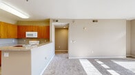 Located at 755 E Capitol Ave in Milpitas, CA, this two-bedroom, one-bathroom residence is thoughtfully laid out across a single floor. The open-concept living room is bright and inviting, featuring wall-to-wall carpet, neutral beige tones, and a large sliding glass door that opens to a balcony overlooking surrounding greenery and the neighborhood beyond. The kitchen is efficiently designed with warm wood cabinetry, granite-style countertops, a peninsula breakfast bar, and white appliances including a refrigerator, electric range, and microwave. Tile flooring in the kitchen provides a clean contrast to the carpeted living areas. The primary bedroom is generously sized, benefiting from natural light streaming through a sliding glass door that also accesses the balcony, and includes a dedicated closet. The second bedroom is a comfortable, well-proportioned space with its own closet and carpeted floors. A hallway connects the rooms and leads to the full bathroom, which features a wood-toned vanity with a granite-style countertop, a large mirror, tile flooring, and a shower-tub combination. The unit is finished with consistent neutral wall colors and clean white trim throughout, creating a cohesive and functional living environment.
