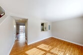 Located at 18 Lawrence St in Boston's Brighton neighborhood, this two-story home offers three bedrooms and one bathroom across two well-proportioned floors. Warm hardwood flooring runs consistently throughout the space, lending a cohesive and inviting feel to every room.

The first floor features a welcoming entrance that leads into a bright living room, bathed in natural light that reflects off the hardwood floors. A pass-through window connects the living and dining areas to the kitchen, creating an open, communicative flow between spaces. The staircase, visible from the dining area, anchors the main floor's layout with clean, simple lines.

The kitchen is equipped with stainless steel appliances, including a full-size refrigerator, and is complemented by white cabinetry. A dedicated laundry area with a stacked washer and dryer unit provides added convenience within the home.

Upstairs, three bedrooms each feature hardwood floors, ample natural light from windows with blinds, individual wall-mounted AC units, and baseboard heating — ensuring year-round comfort. The primary bedroom offers generous space. The shared full bathroom is clean and modern, outfitted with a white shaker-style vanity, built-in cabinet storage, and bright overhead lighting. Four closets distributed throughout the home provide practical storage solutions.