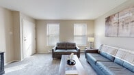 Located at The Grand At Neshaminy in Bensalem, Pennsylvania, this single-floor residence offers a well-organized layout that balances comfort and functionality. The living room serves as a welcoming central space, featuring soft carpeting, neutral wall tones, and two large windows fitted with horizontal blinds that allow generous natural light to fill the room. The open, uncluttered design provides ample space for seating arrangements.

Adjacent to the living area, a dedicated dining space accommodates a full-sized table and chairs beneath a classic pendant light fixture, creating a defined area well-suited for everyday meals or entertaining. The kitchen is equipped with rich, dark-stained wood cabinetry, granite-style countertops, a stainless steel sink with a pull-down faucet, and black appliances including a range with overhead ventilation. Durable vinyl plank flooring completes the kitchen's practical aesthetic.

The residence includes two carpeted bedrooms, each featuring multiple windows that bring in natural light and offer a calm, restful atmosphere. The bathroom includes tile flooring, a wood-toned vanity with a granite-style countertop, and a tub and shower combination enclosed by sliding glass doors, providing a clean and functional design throughout.