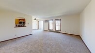 Located at 7718 Radcliffe Drive in Madison, WI, this 2-bedroom, 1-bathroom unit offers a well-organized, single-floor layout designed for comfortable everyday living. The open living room is generously proportioned, featuring neutral carpet flooring, warm wood-trimmed windows, a ceiling fan, a sliding door that brings in natural light, and a baseboard heating system. A pass-through opening connects the living area to the kitchen, enhancing the sense of openness. The galley-style kitchen is efficiently laid out with warm oak cabinetry, dark countertops, a double-basin sink, and a full suite of appliances including a stainless electric range, built-in microwave, dishwasher, and refrigerator, all set on easy-care tile-style flooring. Both bedrooms are carpeted and bright, with natural light from wood-trimmed windows. The primary bedroom offers a spacious footprint with two closets — one featuring built-in shelving — providing excellent storage. The second bedroom also includes closet space. The full bathroom is clean and functional, featuring a tub/shower combination with grab bars and a curtained surround. A dedicated in-unit laundry area accommodates a full-size washer and dryer with overhead shelving for added utility.