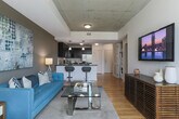 Located in Atlanta's vibrant Old Fourth Ward neighborhood, this modern single-floor residence offers a thoughtfully designed open-concept layout that seamlessly connects the kitchen, dining, and living areas. The kitchen is a standout feature, boasting dark cabinetry, granite countertops, stainless steel appliances—including a French door refrigerator, electric range, and built-in microwave—along with a white subway tile backsplash and pendant lighting over a two-seat breakfast bar. Warm hardwood floors flow throughout the main living areas, complementing the neutral-toned walls and exposed concrete ceiling accents that add an industrial character to the space. The living room is bright and inviting, benefiting from floor-to-ceiling windows that frame urban views and allow abundant natural light, with access to a private balcony. The bedroom continues the floor-to-ceiling window theme, offering sweeping city views and plush carpeting for comfort. The bathroom features a glass-enclosed walk-in shower with large white subway tiles, a dark-vanity with granite countertop, and clean tile flooring. An in-unit laundry area adds everyday convenience to this well-appointed urban residence.