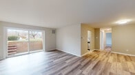 This single-floor residence showcases a thoughtfully updated interior with a consistent, modern aesthetic carried throughout each room. Light-toned luxury vinyl plank flooring runs continuously across the living areas, bedrooms, and bathroom, creating a cohesive and clean look underfoot.

The open living area is bright and airy, benefiting from a sliding glass door that invites natural light and provides outdoor access. A hallway connects the living space to the kitchen and private rooms, maintaining an efficient and practical layout.

The kitchen is outfitted with stainless steel appliances, including an electric range, over-the-range microwave, and dishwasher. Gray shaker-style cabinetry pairs with granite-look countertops, while a white subway tile backsplash adds a classic, polished touch.

The bedrooms are well-proportioned, each featuring neutral wall tones, white trim, and windows that frame outdoor views. One bedroom includes a double-door closet for storage convenience.

The bathroom is finished with marble-look large-format tile surrounding the tub and shower combination, complemented by a gray vanity with a white countertop, brushed nickel fixtures, and a framed mirror with sconce lighting, creating a clean and contemporary feel.