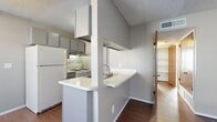 This single-floor, 2-bedroom, 1-bathroom unit offers a practical and efficient layout designed to maximize every square foot. The living room welcomes you at the entrance with rich, dark hardwood-style flooring, neutral taupe walls, a textured ceiling, and a window fitted with blinds that allows natural light to fill the space.

The kitchen is designed in a galley style, featuring gray cabinetry, white countertops, a stainless steel sink, and a full suite of appliances including a gas range and refrigerator. A peninsula with a pass-through counter connects the kitchen to the hallway, adding a sense of openness to the layout. The kitchen also includes a built-in pantry closet for additional storage.

Both bedrooms are carpeted and finished with neutral walls and textured ceilings. Each room benefits from windows with blinds, providing natural light and privacy. The primary bedroom offers a comfortable footprint with closet access. A second closet is also available elsewhere in the unit, contributing to ample storage throughout.

The bathroom is clean and functional, featuring a combined tub and shower unit, a wood-vanity with countertop, a toilet, and hardwood-style flooring. A hallway connects all rooms, creating a logical and convenient flow throughout the home.