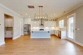 Located at 3110 Doe River Way in Matthews, NC, this two-story home offers a well-designed layout across two floors, combining modern finishes with functional living spaces. The exterior features classic gray lap siding with white trim, a covered front porch, and landscaped surroundings with a fenced yard.

The main floor hosts an open-concept kitchen and living area bathed in natural light. The kitchen is a standout, showcasing white shaker cabinetry extending to the ceiling with glass-front upper cabinets, sleek quartz countertops, a large center island, stainless steel appliances including a gas range with hood, and light hardwood flooring throughout. The living area features crown molding, recessed lighting, and a ceiling fan.

Upstairs, the generous primary bedroom includes a tray ceiling, ceiling fan, plush carpeting, and multiple windows overlooking greenery. The en-suite bathroom features a frameless glass walk-in shower with hexagonal tile, a dual-sink vanity with quartz countertops, and hardwood flooring. Seven closets provide ample storage throughout the home.

Additional highlights include a dedicated laundry room with side-by-side washer and dryer, a pantry, an attached garage, and two patio spaces ideal for outdoor living.
