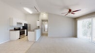 This single-story, 3-bedroom, 2-bathroom home offers a practical and comfortable layout across one level. The open living area immediately impresses with vaulted ceilings and a ceiling fan, creating an airy and spacious atmosphere. Plush carpeting flows throughout the living and bedroom areas, while light-toned ceramic tile defines the kitchen and wet areas.

The kitchen is well-equipped and functional, featuring white cabinetry, dark granite-style countertops, stainless steel appliances including a refrigerator, electric range, built-in microwave, and dishwasher. A peninsula counter opens toward the living area, enhancing the sense of connectivity between spaces. Track lighting above the kitchen provides ample illumination.

The primary bedroom is generously sized with a walk-in closet outfitted with wire shelving for organized storage. The additional bedrooms are comfortably proportioned, each with soft carpeting and windows that invite natural light and outdoor views. The two bathrooms are clean and efficiently designed, with one featuring a full tub-shower combination and tile flooring.

A dedicated laundry room accommodates a full-size side-by-side washer and dryer, adding everyday convenience. The hallway connects the rooms efficiently, and multiple closets throughout the home provide ample storage. The living room includes a sliding glass door with vertical blinds, allowing for natural light and outdoor access.
