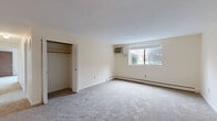 Located at 17 Conant Street in Beverly, MA, this single-floor residence offers three bedrooms, one bathroom, a kitchen, and a hallway, all arranged in a practical and cohesive layout. The generously sized primary bedroom stands out for its spaciousness, featuring plush wall-to-wall carpeting, a large window that brings in natural light with views of the surrounding greenery, a wall-mounted air conditioning unit, and a built-in closet with a bifold door. The second and third bedrooms are also carpeted and naturally lit, each with its own closet for storage convenience. The living area is open and airy, accented by a chandelier and neutral walls that create a clean, inviting ambiance. The kitchen is equipped with dark wood cabinetry, tile backsplash, a built-in range with overhead ventilation, a full-size refrigerator, and a stainless steel sink. The bathroom features classic white tile surround, a tub-shower combination, mosaic tile flooring, and direct access to an additional walk-in closet with built-in shelving and hanging rods. Baseboard heating is present throughout, and the neutral color palette and carpet flooring lend a consistent, comfortable feel to the entire residence.
