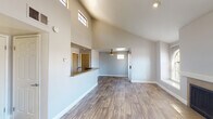 This single-floor residence makes a striking first impression with its dramatic vaulted ceilings that soar above the open-concept living area, enhanced by clerestory windows that flood the space with natural light. Wood-look plank flooring runs throughout the main living areas, complementing the neutral gray tones on the walls and creating a cohesive, modern aesthetic. A ceiling fan with a window above the front entry adds both function and character to the living room.

The kitchen is thoughtfully designed with a raised peninsula that opens to the living area, making it ideal for both daily use and entertaining. Gray shaker-style cabinetry, granite-look countertops, and a full suite of stainless steel appliances — including a refrigerator, microwave, and range — complete the space with a clean, contemporary look.

The bedrooms are carpeted for comfort, with neutral walls and an abundance of natural light from well-placed windows. One bedroom features a built-in closet with shelving, providing organized storage. The bathrooms are finished with matching gray cabinetry, granite-look countertops, wood-look tile flooring, and a tub-shower combination, offering a consistent and polished design throughout the home.