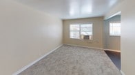 Located at 980 Palm Ave in the heart of West Hollywood, CA, this single-floor unit offers a well-organized and functional layout. The living area is finished with neutral beige walls and plush carpeting, creating a warm and welcoming atmosphere. A wall heating unit and a clean white entry door add to the practicality of the space. The bedroom continues the same neutral palette with carpeted floors, a window fitted with blinds, and a wall air conditioning unit, providing a comfortable and private retreat. The kitchen is equipped with stainless steel appliances, including a gas range and an over-the-range microwave, complemented by modern white cabinetry with frosted glass upper doors, a compact sink, and tile flooring — offering a sleek, contemporary feel. The bathroom features slate-blue tile flooring, a pedestal sink, a full bathtub with a shower curtain, and a frosted window above the tub that allows natural light to enter while maintaining privacy. The walls are accented in a soft aqua tone, adding a refreshing touch to the space. Overall, the unit presents a clean, move-in-ready environment with a cohesive design that balances modern updates with comfortable, everyday livability.