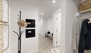 This two-bedroom, one-bathroom unit at Citizen On Jasper offers a thoughtfully designed layout that maximizes functionality within a compact footprint. The open-concept kitchen and living area serves as the heart of the space, featuring light hardwood-style flooring that extends throughout. The kitchen is outfitted with two-tone cabinetry, white quartz countertops, a subway tile backsplash, stainless steel appliances including a built-in microwave and full range, and track lighting overhead. A small dining area adjacent to the kitchen provides a dedicated space for meals.

The living room is bright and airy, anchored by large floor-to-ceiling windows that frame city views and flood the space with natural light. The entryway features recessed lighting, a built-in bench, and clean white walls that carry throughout the unit.

Both bedrooms are compact yet functional, with the primary bedroom benefiting from a large window offering urban views. The shared bathroom includes a wood-grain vanity with a white countertop, a combined tub and shower, and light tile flooring. The overall aesthetic is clean and contemporary, characterized by a neutral white palette and modern finishes.