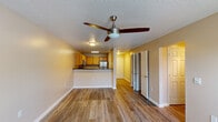 Located at 970 Spring Forest Rd in Greenville, NC, this single-floor unit offers a practical and well-organized layout with consistent design elements throughout. Wood-look luxury vinyl plank flooring runs throughout the entire space, providing a cohesive and durable foundation. Textured ceilings and neutral warm-beige walls create a clean, understated backdrop in every room.

The living area is generously proportioned, featuring a ceiling fan with integrated lighting and a glass door that allows natural light to pour in while offering outdoor access. This space flows directly into the kitchen, which is accessible via a peninsula counter topped with dark granite-style laminate. The kitchen is equipped with warm oak cabinetry, stainless steel appliances including a refrigerator and microwave, and a built-in range, all illuminated by recessed fluorescent lighting above.

The bedrooms are spacious and well-lit, each featuring ceiling fans and large windows. At least one bedroom includes a walk-in closet with wire shelving. The bathroom is outfitted with a full-sized tub and shower combination, a long vanity with oak cabinetry, white countertops, and a large mirror, with direct access connecting to an adjacent bedroom for added convenience.