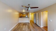 Located at 970 Spring Forest Rd in Greenville, NC, this single-floor unit offers a practical and well-organized layout with consistent design elements throughout. Wood-look luxury vinyl plank flooring runs throughout the entire space, providing a cohesive and durable foundation. Textured ceilings and neutral warm-beige walls create a clean, understated backdrop in every room.

The living area is generously proportioned, featuring a ceiling fan with integrated lighting and a glass door that allows natural light to pour in while offering outdoor access. This space flows directly into the kitchen, which is accessible via a peninsula counter topped with dark granite-style laminate. The kitchen is equipped with warm oak cabinetry, stainless steel appliances including a refrigerator and microwave, and a built-in range, all illuminated by recessed fluorescent lighting above.

The bedrooms are spacious and well-lit, each featuring ceiling fans and large windows. At least one bedroom includes a walk-in closet with wire shelving. The bathroom is outfitted with a full-sized tub and shower combination, a long vanity with oak cabinetry, white countertops, and a large mirror, with direct access connecting to an adjacent bedroom for added convenience.