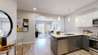 Located at 70 Park East Dr in Winnipeg, MB, this well-appointed 2-bedroom, 1-bathroom unit offers a thoughtfully designed open-concept layout across a single floor. Light-toned luxury vinyl plank flooring runs throughout the main living areas, complementing the bright, neutral palette.

The kitchen is a standout feature, showcasing two-tone cabinetry with sleek high-gloss white upper cabinets and charcoal lower cabinets, white quartz countertops, a tiled subway backsplash, and a full suite of stainless steel appliances including a range, microwave, dishwasher, and refrigerator. A central island with an undermount sink and bar seating provides additional prep space and casual dining.

The open living area flows seamlessly from the kitchen and is anchored by a sliding glass door leading to a private balcony overlooking the surrounding neighbourhood, filling the space with natural light. The spacious primary bedroom offers a generous footprint with a large window, while the second bedroom provides comfortable accommodations with natural light of its own.

The full bathroom features tile flooring, a tub-shower combination, and a white vanity with modern fixtures. Recessed lighting and pendant fixtures throughout add a refined, contemporary feel to this functional and stylish home.