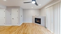 Located at 3O Madelyn Way in Laconia, NH, this three-floor townhouse offers a thoughtfully designed layout across its three levels. The ground floor provides an attached garage with automatic opener, clean concrete flooring, and interior access — offering convenient, secure parking and additional storage. The main living level features a bright, open kitchen outfitted with slate-blue shaker cabinetry, quartz countertops, white subway tile backsplash, and a full suite of stainless steel appliances including a French door refrigerator, range, built-in microwave, and dishwasher. Warm hardwood flooring flows throughout. The adjacent living room is highlighted by a tiled gas fireplace, a sleek ceiling fan with integrated lighting, and a sliding glass door that invites natural light. The upper floor houses three bedrooms, each carpeted for comfort. The primary bedroom offers a generous footprint, while the additional bedrooms include features such as sliding closet doors and natural light from windows. A full bathroom with tile flooring, a vanity with white countertop, and black matte fixtures serves the upper level. Neutral gray tones and clean finishes throughout lend the home a fresh, modern aesthetic.
