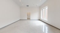 Located at 78-80 Middlesex St in Lowell, Massachusetts, this one-bedroom, one-bathroom unit offers a clean, modern design across a single floor. The open living and kitchen area is immediately welcoming, featuring striking polished terrazzo floors that reflect natural light and lend a bright, airy quality to the space. Soaring ceilings amplify the sense of openness throughout the main living area, which is bathed in natural light from large windows that frame views of the surrounding brick architecture.

The kitchen is efficiently designed with crisp white cabinetry, ample counter space, and a full suite of stainless steel appliances, including a refrigerator, range, dishwasher, and over-the-range microwave. A louvered storage closet provides additional organizational convenience near the entry.

The bedroom is a comfortable, well-proportioned retreat with soft carpeted flooring and a large window that brings in natural light. The clean white walls and simple layout offer a calm, restful atmosphere.

The bathroom is finished in an all-white palette, featuring a tub-shower combination with built-in shelving, a single vanity, and terrazzo-style flooring consistent with the unit's cohesive aesthetic. A hallway connects the rooms, contributing to the functional and straightforward flow of the layout.