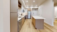 Located in Millcreek, Utah, this well-appointed 2-bedroom, 2-bathroom residence offers a thoughtfully designed single-level layout with modern finishes throughout. Light-toned hardwood flooring flows seamlessly across the entire space, complementing the clean, neutral color palette.

The open-concept living area connects the kitchen, dining, and living rooms into one cohesive space bathed in natural light. The kitchen is a standout feature, equipped with stainless steel appliances — including a refrigerator, range, microwave, and dishwasher — paired with two-tone cabinetry in warm taupe and crisp white. A white quartz island provides additional prep and seating space, while a subway tile backsplash adds a polished finishing touch.

The primary bedroom offers generous proportions with recessed lighting and direct access to a spacious walk-in closet with built-in shelving and hanging rods. The en-suite primary bathroom features a dual-sink vanity with quartz countertops, warm wood cabinetry, and a large mirror with overhead lighting. The second bathroom includes a full soaking tub and shower combination with built-in shelving.

The second bedroom benefits from a large picture window framing scenic mountain views. Additional highlights include an in-unit laundry room, a utility room, and a private balcony. Recessed lighting throughout lends the space a bright, modern ambiance.