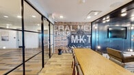 This thoughtfully designed amenity space spans a single floor and seamlessly blends industrial character with modern sophistication. At the heart of the interior, an exposed brick accent wall bearing a vintage M-K-T railroad mural serves as a striking focal point, adding historic charm to the contemporary setting. Light hardwood flooring flows throughout, complementing the bold contrast of dark steel-framed glass partitions that divide the space into distinct yet visually connected zones.

The main lounge area features a comfortable seating arrangement alongside a dining table, ideal for both casual gatherings and collaborative use. A sleek wet bar runs along one wall, complete with stainless steel appliances, a sink, and white quartz countertops beneath a dramatic dark paneled ceiling fitted with directional track lighting. Large sliding windows at the bar connect directly to the outdoor terrace, blurring the boundary between interior and exterior.

The covered outdoor terrace is finished with decorative patterned tile and framed by exposed brick walls, offering bar-height seating, lounge furniture, and sweeping open views of the surrounding cityscape. A dedicated game area within the space features a foosball table and additional lounge seating, creating a lively recreational zone. Together, these areas deliver a versatile, atmosphere-rich environment suited for socializing and relaxation.