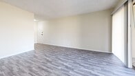 Located at 2002 Stoneycreek Dr in High Point, NC, this well-appointed 2-bedroom, 2-bathroom single-story residence offers a practical and comfortable layout across a thoughtfully organized floor plan. The living room is generously sized, featuring cool-toned gray wood-look flooring, neutral walls, and a textured ceiling. A sliding glass door floods the space with natural light and provides direct access to an outdoor patio area, while a secondary window adds additional brightness. The kitchen is equipped with gray-painted cabinetry, light speckled countertops, a double-coil electric range, a built-in dishwasher, and an overhead exhaust fan — all set atop matching wood-look flooring. Both bathrooms feature white vanities with stone-style countertops, framed mirrors, and matte black hardware accents that lend a modern touch. The two bedrooms are carpeted in a warm neutral tone, each receiving natural light through windows with exterior views. The primary bedroom includes a walk-in closet with built-in shelving. A hallway connects the rooms and provides a well-defined flow throughout the home. The overall aesthetic is clean, bright, and move-in ready.