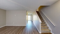 Located at 200 Canaan Pointe Dr in Spartanburg, SC, this two-story home offers four bedrooms and two full bathrooms thoughtfully distributed across two floors. The main level features warm wood-look flooring that flows through the open living area and along a bright hallway, which draws in natural light from a large window at its end. A carpeted staircase with white railings connects the floors, and textured ceilings add character throughout. The kitchen is a galley-style layout featuring rich, dark wood cabinetry with gold hardware, white laminate countertops, a stainless steel sink, and a white electric range with overhead ventilation. Both bathrooms are clean and functional, each equipped with a tub-shower combination and chrome fixtures; one features wood-look flooring and a warm wood vanity. The bedrooms are carpeted and finished in neutral tones, with several rooms featuring ceiling fans and windows that invite natural light. Closets provide practical storage, including a built-in rod closet visible in one of the upper-floor bedrooms. The upper floor offers slightly more square footage than the main level, accommodating the majority of the bedrooms. The home's neutral color palette and consistent finishes create a cohesive, move-in-ready feel throughout.