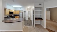 This single-floor residence offers a thoughtfully designed layout that balances functionality and comfort throughout its living spaces. The open-concept kitchen serves as a central hub, outfitted with light maple cabinetry, dark countertops, and a full suite of stainless steel appliances including a refrigerator, range, microwave, and dishwasher. A peninsula with a built-in sink provides additional workspace and casual dining potential. Adjacent to the kitchen, built-in shelving offers convenient display and storage space, while a hallway leads to the bathroom and additional rooms.

The bedrooms feature plush carpeting, ceiling fans, and windows fitted with horizontal blinds that allow for adjustable natural light. Each room benefits from generous closet access, contributing to practical everyday living.

The bathroom is clean and efficiently arranged, featuring a vanity with a single-basin sink, warm wood-toned cabinetry, and a mirrored medicine cabinet. Dark wood-look flooring grounds the space, complementing the white tiled tub-shower surround. Recessed lighting provides bright, even illumination throughout. Overall, the neutral color palette of warm grays and whites lends the residence a clean, move-in ready aesthetic.