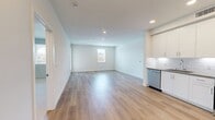 Located at 30950 Hanover Ln, Unit 14-205 in Menifee, CA, this single-story residence offers 1,260 square feet of thoughtfully designed living space across 4 bedrooms and 2 bathrooms. The kitchen is a standout feature, outfitted with crisp white shaker cabinetry, grey countertops, a white subway tile backsplash, and a full suite of stainless steel appliances including a gas range, over-the-range microwave, dishwasher, and refrigerator. Light wood-look flooring flows throughout the main living areas and bathrooms, creating a clean, cohesive aesthetic. Both bathrooms are finished with wood-look flooring, white tub-shower combinations with tiled surrounds and built-in shelving, and one features a single-sink vanity with a dark countertop and mirror. The four bedrooms offer a mix of flooring — some with soft carpet and others with light wood-look floors — and each is brightened by windows with blinds overlooking the surrounding community. Three closets provide generous storage, including walk-in closets equipped with wire shelving and hanging systems. The unit's neutral color palette of whites and light greys throughout lends a modern, move-in-ready ambiance.