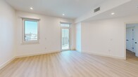 Located at 20 Medford St in Somerville, MA, this thoughtfully designed one-bedroom, one-bathroom residence offers a clean, modern aesthetic with high-quality finishes throughout. Light oak hardwood flooring runs continuously across the open-plan layout, complemented by crisp white walls and recessed lighting that create a bright, airy atmosphere.

The combined kitchen and living area serves as the heart of the home. The kitchen features a large waterfall-edge quartz island with an undermount sink and matte black faucet, warm wood cabinetry on the lower island, white upper cabinetry, stainless steel appliances including a range and built-in microwave, and stylish smoked glass pendant lights overhead.

The bedroom is a well-proportioned retreat bathed in natural light from multiple windows, with direct access to a private balcony offering outdoor views. The room includes a double-door closet with matte black hardware, and the unit additionally benefits from four closets total, providing exceptional storage.

The bathroom is finished in a contemporary style with large-format tile flooring, a wood-toned vanity with quartz countertop, matte black fixtures, and a glass-enclosed shower. An in-unit laundry room and a utility room add everyday convenience to this well-appointed Somerville residence.