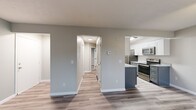 Located at 2450 County Road 28 in Canandaigua, NY, this 2-bedroom, 1-bathroom unit offers a thoughtfully designed single-floor layout with modern finishes throughout. The entrance opens into a bright, open living room featuring durable wood-look flooring, a ceiling fan with light fixture, and a large sliding door with vertical blinds that invites natural light. The galley-style kitchen is well-equipped with white shaker upper cabinets, gray lower cabinets, granite-look countertops, stainless steel appliances including a refrigerator, electric range, microwave, and dishwasher, all set over matching wood-look flooring. A hallway connects the main living areas to both bedrooms and the shared bathroom. The primary bedroom offers generous space with a sliding double-panel closet and plush carpet flooring. The second bedroom also features carpet flooring, a window with blinds, and baseboard heating. The full bathroom is finished with a white vanity, granite-look countertop, a large mirror with overhead lighting, and a tub-shower combination. Clean neutral tones and consistent finishes create a cohesive, move-in-ready ambiance throughout the entire space.