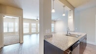 This well-appointed 3-bedroom, 2-bathroom single-story home in Austin, TX offers a thoughtfully designed open-concept layout that maximizes both space and functionality. The combined kitchen and living area serves as the heart of the home, where the kitchen impresses with rich dark espresso cabinetry, granite countertops, a subway tile backsplash, stainless steel appliances, and elegant pendant lighting over the breakfast bar. The living room is bright and inviting, featuring hardwood-style flooring, a ceiling fan, track lighting, and a wall of windows with a glass door that floods the space with natural light. The bedrooms offer plush carpeting and ceiling fans, with the generously sized primary bedroom providing a comfortable retreat. The primary bathroom is well-equipped with a dual-sink vanity featuring dark cabinetry, a walk-in shower with white tile surround, and wood-style flooring. The secondary bathroom includes a soaking tub with a clean white tile surround. Additional highlights include built-in shelving in one of the secondary rooms, two closets, and a neutral warm-toned color palette throughout that creates a cohesive and welcoming ambiance across the entire home.
