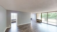 This single-floor residence offers a well-organized layout designed for comfortable everyday living. The expansive living and dining area is finished with durable hardwood-style flooring and neutral gray walls, creating a bright and open atmosphere. Large sliding glass doors lead to a private balcony, framing lush tree views and flooding the space with natural light. Wall-mounted PTAC units provide individual climate control throughout the unit.

The kitchen features warm wood cabinetry, granite-style countertops, and a full suite of appliances including a refrigerator, dishwasher, and range. A checkered tile floor adds a classic touch to this functional cooking space.

The bedrooms are carpeted for comfort and painted in soft gray tones, each benefiting from generous windows with outdoor views and individual climate control units. Closet storage is present in the bedroom areas, offering practical organization solutions.

The bathroom is cleanly appointed with a tiled tub and shower surround, a white vanity with storage, a mirrored medicine cabinet, and a three-bulb vanity light fixture. Textured ceilings are consistent throughout the unit, and crisp white baseboards provide a clean finish across all rooms.