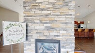 Located in Forest, Virginia, this single-floor space offers an open-concept layout designed for both comfort and functionality. The main living area immediately impresses with soaring vaulted ceilings and a dramatic floor-to-ceiling stacked stone fireplace, which serves as the room's central focal point. A wall-mounted television above the fireplace and a ceiling fan overhead add practical touches to the grand aesthetic. Large windows throughout allow abundant natural light to fill the space, enhancing its airy, welcoming atmosphere. Rich, large-format tile flooring runs throughout, providing a warm and cohesive look.

The living and dining areas flow seamlessly together, separated by elegant French doors that add a refined architectural detail. The dining area accommodates a modest table and chairs, making it ideal for casual gatherings. The kitchen is thoughtfully designed with rich cherry wood cabinetry, granite countertops, a classic subway tile backsplash, and a full suite of stainless steel appliances. A generous kitchen island with bar seating and pendant lighting above creates a natural hub for entertaining. Together, these spaces combine architectural character with everyday practicality in a bright, open, and inviting environment.