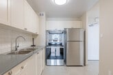 Located at 2969 Kingsway Dr in Kitchener, Ontario, this 2-bedroom, 1-bathroom unit offers a well-organized and functional layout spread across a single floor. The space is characterized by warm parquet flooring that runs throughout the living areas and bedrooms, giving the unit a cohesive and classic feel.

The combined kitchen and living room area is generously proportioned, with large floor-to-ceiling windows that flood the space with natural light and frame open outdoor views. The living area provides ample room for comfortable furnishing arrangements, while the kitchen features white cabinetry, grey countertops, and subway tile backsplash accents. A hallway connects the main living area to the private quarters.

Both bedrooms are well-sized, with the primary bedroom offering notable space and a large sliding door closet. Each bedroom benefits from access to natural light, and the primary bedroom features a sliding glass door that opens to a balcony with open views of the surrounding area.

The bathroom is finished with crisp white subway tile surrounding a full soaker tub and shower combination, complemented by brushed nickel fixtures for a clean, updated look. The entry hallway provides a practical transition into the unit. Overall, the space presents a bright, neutral palette throughout, making it a versatile and inviting home.