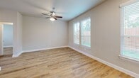 Located in Conroe, TX, this single-story, 2-bedroom, 2-bathroom home offers a clean, modern aesthetic throughout its thoughtfully designed floor plan. Light wood-look flooring runs consistently across all rooms, complemented by neutral warm-gray walls and crisp white trim, creating a cohesive and contemporary feel.

The kitchen is a standout feature, showcasing white shaker-style cabinetry extending to the ceiling for ample storage, a white subway tile backsplash, light quartz countertops, a center island, and a full suite of stainless steel appliances including a refrigerator, range, microwave, and dishwasher. The kitchen flows openly into the living area, enhancing the sense of space.

Both bedrooms are well-proportioned, each featuring ceiling fans, natural light from double windows with blinds, and views of the surrounding greenery. The spacious primary bedroom includes a private en-suite bathroom with a glass-enclosed shower, white vanity, and matte black hardware accents. The second bathroom offers a tub-shower combo, a white vanity, and a natural light window.

Additional highlights include multiple closets, a dedicated laundry area, and an outdoor patio surrounded by a wood privacy fence and mature trees. Recessed lighting and matte black fixtures add polished, modern detail throughout.