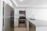 Located at 65 Times Ave in Markham, Ontario, this well-appointed one-bedroom, one-bathroom unit offers a functional and efficient layout across a single floor. The open-concept kitchen and living area serves as the heart of the unit, featuring classic parquet hardwood flooring that adds warmth and character. The kitchen is outfitted with stainless steel appliances — including a refrigerator, electric range, and over-the-range microwave — complemented by white cabinetry, a granite-look countertop, a double undermount sink, and a peninsula that provides both additional prep space and a natural division between the kitchen and living area. The living room benefits from a large window fitted with vertical blinds, allowing ample natural light to fill the space. The bedroom is a comfortable, well-sized room with plush carpeting, a large window overlooking greenery, and a ceiling vent for climate control, creating a bright and peaceful retreat. The bathroom features tile flooring, a bathtub with a shower, and clean white finishes throughout. The unit maintains a neutral, light colour palette with white walls and ceilings, contributing to an airy and cohesive ambiance throughout.