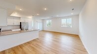 Located at 1024 Romneya Dr in Anaheim, California, this single-floor, 3-bedroom, 2-bathroom home offers a clean, contemporary design with thoughtful finishes throughout. The open-concept kitchen and living area forms the heart of the home, featuring light hardwood-style flooring, recessed lighting, and large windows that invite abundant natural light. The kitchen is equipped with stainless steel appliances, including an electric range and over-the-range microwave, complemented by white shaker cabinetry, grey quartz countertops, and a classic white subway tile backsplash. The spacious living area extends seamlessly from the kitchen, offering generous room for entertaining or relaxing. The three bedrooms are carpeted in a neutral tone, each with white walls and ample natural light. The primary bedroom is notably spacious and includes a sliding-door closet. The two bathrooms are finished in a crisp, modern style — one features a full tub/shower combo with white tile surround, while the other includes a dual-sink vanity with grey countertops, a large mirror, and hardwood-style flooring. A connecting hallway ties all rooms together efficiently, completing this well-laid-out, move-in-ready home.