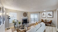 Located at 1802 Apollo Rd, this single-floor residence offers a thoughtfully designed layout with a warm, contemporary aesthetic. The living room serves as the heart of the home, anchored by a classic wood-mantel fireplace and accented by light wood-style flooring that flows throughout the space. A sliding glass door opens to a private balcony, allowing natural light to fill the room and creating a seamless connection to the outdoors. A dedicated dining area sits adjacent to the living space, ideal for everyday meals or entertaining.

The kitchen features gray cabinetry, updated countertops, and a clean, functional layout with light wood flooring continuing from the main living areas. A textured ceiling is consistent throughout the residence, adding depth to each room.

The bedroom is generously sized with a ceiling fan, ample natural light from shuttered windows, and access to a walk-in closet — offering both comfort and practical storage. The bathroom is well-appointed with gray vanity cabinetry, a white quartz countertop, an undermount sink, and a framed mirror with brushed nickel hardware. Tiled shower walls complete the refined finish of this private retreat.