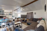 Located at 2664 Pineapple Avenue in Melbourne, Florida, this single-story 2-bedroom, 2-bathroom home offers a compact yet functional layout designed to maximize every inch of its space. The open-concept living, dining, and kitchen area forms the heart of the home, creating a connected and social atmosphere. The living room features wood-look flooring, a vaulted ceiling with exposed wood beams, and a ceiling fan, lending a casual, relaxed character to the space. The kitchen is well-equipped with white cabinetry, dark countertops, a stainless steel refrigerator, a white range, and a window above the sink that brings in natural light. A dining area sits adjacent to the kitchen, completing the open common area. Both bedrooms feature warm wood-paneled walls that give each room a cozy, cottage-like feel, with carpeted flooring and ceiling light fixtures. The primary bedroom includes a mirrored closet with ample storage. The two bathrooms include shower/tub combinations and windows for ventilation. A dedicated laundry area and an entrance hallway with louvered closet doors add everyday convenience. A thermostat is accessible from the hallway, and the entrance provides a welcoming transition into the home's main living spaces.