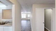 Located at 214 Caprano Dr in Holly Springs, NC, this single-story, 3-bedroom, 1-bathroom home offers a practical and well-organized layout. The living room greets you with an open, airy feel, featuring dark wood-style flooring, neutral-toned walls, a textured ceiling, and windows that invite natural light and outdoor views. A central hallway connects the main living areas to the bedrooms seamlessly. The kitchen is well-equipped with white cabinetry, granite-style countertops, a coil-burner electric range, a full-size refrigerator, and a window above the sink that brightens the workspace. The bedrooms feature soft carpeting and neutral walls, offering a comfortable retreat. The primary bedroom is generously sized and includes a closet and direct access to the bathroom. The full bathroom is outfitted with a combination tub and shower unit. A dedicated laundry room with hookups, overhead shelving, and matching wood-style flooring adds everyday convenience. Throughout the home, consistent finishes including dark hardwood-style floors in the main areas and white trim create a cohesive, clean aesthetic suited for comfortable living.
