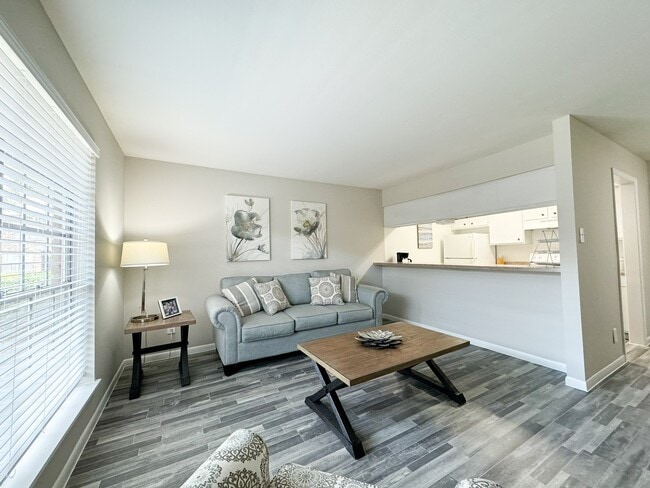 Sala de estar con tonos suaves y luz solar. - Memorial City Apartments