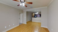 This well-designed two-story, 3-bedroom, 2.5-bathroom home offers a thoughtful layout with quality finishes throughout. The main level features warm hardwood flooring that flows through the living and dining areas, complemented by crown molding and ceiling fans that add a classic touch. Natural light filters in through windows fitted with blinds, brightening the open living space. The kitchen is a standout feature, showcasing rich dark cherry cabinetry, a tile backsplash, light-toned countertops, and black appliances including a refrigerator, range, and built-in microwave. A pass-through opening connects the kitchen to the living area, enhancing the open-concept feel. A convenient half-bath is located on the main level. The main level also includes a dedicated laundry room with tile flooring and built-in shelving. Upstairs, the bedrooms are carpeted for comfort, each equipped with ceiling fans and closet space. The primary bathroom features a double vanity with dark cabinetry, tile flooring, and a separate water closet. Additional bedrooms share access to a well-appointed full bathroom. The home's consistent use of neutral tones, crown molding, and cohesive finishes creates a warm, comfortable living environment throughout.