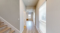 This two-story home offers a thoughtfully designed layout spread across two levels, with the lower floor housing the garage and main living areas, and the upper floor dedicated to the bedrooms and additional bathrooms. Light wood-tone flooring runs consistently throughout the home, creating a cohesive and clean aesthetic complemented by neutral wall tones and crisp white trim.

The kitchen and living area occupy a combined open-plan space, where the kitchen stands out with white shaker-style cabinetry, granite countertops, a subway tile backsplash, and a full suite of stainless steel appliances including a refrigerator, range, and over-the-range microwave. The upper level is anchored by a generously sized primary bedroom featuring a ceiling fan, natural light from windows with blinds, and access to a walk-in closet with built-in shelving and hanging rods. Two additional bedrooms, each with ceiling fans and light-filled windows, provide comfortable accommodations. Four bathrooms serve the home, finished consistently with the overall clean, modern palette. A dedicated laundry room on the upper level includes a full-size washer and dryer with overhead cabinetry for storage. The attached two-car garage features an automatic opener and offers ample space for vehicles and additional storage.