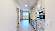 Located at 44 High St in downtown Nashua, New Hampshire, this efficiently designed single-floor unit offers a thoughtfully organized layout that maximizes every square foot. The combined kitchen and living area serves as the heart of the space, featuring light wood-tone flooring that runs seamlessly throughout, neutral warm-toned walls, and large windows that invite abundant natural light and frame views of the surrounding cityscape. A ceiling fan adds both function and visual interest to the living area.

The kitchen is well-appointed with white shaker-style cabinetry, gleaming quartz countertops, stainless steel appliances including a refrigerator, dishwasher, built-in microwave, and oven, as well as an under-cabinet range hood. A stainless steel undermount sink completes the clean, modern aesthetic.

Two full bathrooms provide convenience and comfort, each finished with light wood flooring, white vanities, and LED-backlit mirrors that lend a contemporary touch. A dedicated closet offers practical storage solutions.

The overall ambiance is bright, clean, and modern, with a cohesive neutral palette that creates an open and airy feel. Situated in the heart of downtown Nashua, the unit offers easy access to local dining, shopping, and transit.