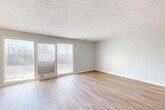 Located at 38 Dillman Dr in Council Bluffs, Iowa, this 2-bedroom, 2-bathroom unit offers a practical and comfortable single-floor layout. The open living room is a bright, welcoming space featuring light wood-look flooring, a textured ceiling, and sliding glass doors that lead to a private balcony with outdoor views. Adjacent to the living area, the kitchen is well-equipped with white cabinetry, granite countertops, light tile flooring, and black appliances including a refrigerator, electric range, and built-in microwave. Both bedrooms are carpeted and feature ceiling fans with integrated lighting and windows that allow natural light to fill each room, creating a comfortable and restful atmosphere. The generously sized primary bedroom provides ample space for furnishings. The bathrooms are clean and functional, with one featuring a tub/shower combination with sliding glass doors, a granite-topped white vanity, and tile flooring. Hallways connect the rooms efficiently throughout the unit, and a dedicated closet provides additional storage. The neutral color palette and consistent finishes throughout lend the space a cohesive, move-in-ready appearance.
