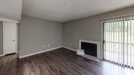 This single-story residence offers a well-organized layout that balances living, dining, and private spaces. The main living area features dark hardwood-style flooring and neutral gray walls, anchored by a classic fireplace with a white surround and a sliding glass door that introduces natural light. The space flows into a dedicated hallway leading to the bedrooms and kitchen.

The kitchen is efficiently designed in a galley style, showcasing rich dark cabinetry, granite-patterned countertops, a double basin sink, and stainless steel appliances including a dishwasher and refrigerator. Light wood-tone flooring completes the clean, functional aesthetic.

Multiple bedrooms are finished with plush carpeting, neutral gray walls, and ceiling fans with light fixtures. Each room benefits from natural light provided by blinds-fitted windows. Closet access is available in the bedrooms.

Both bathrooms feature granite-topped vanities with undermount sinks, framed mirrors with vanity lighting, and dark cabinetry below, maintaining a consistent, updated design throughout. Textured walls add subtle character to these spaces.

Throughout the unit, textured ceilings and consistent neutral tones create a cohesive, move-in-ready atmosphere suited for comfortable everyday living.