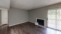 This single-story residence offers a well-organized layout that balances living, dining, and private spaces. The main living area features dark hardwood-style flooring and neutral gray walls, anchored by a classic fireplace with a white surround and a sliding glass door that introduces natural light. The space flows into a dedicated hallway leading to the bedrooms and kitchen.

The kitchen is efficiently designed in a galley style, showcasing rich dark cabinetry, granite-patterned countertops, a double basin sink, and stainless steel appliances including a dishwasher and refrigerator. Light wood-tone flooring completes the clean, functional aesthetic.

Multiple bedrooms are finished with plush carpeting, neutral gray walls, and ceiling fans with light fixtures. Each room benefits from natural light provided by blinds-fitted windows. Closet access is available in the bedrooms.

Both bathrooms feature granite-topped vanities with undermount sinks, framed mirrors with vanity lighting, and dark cabinetry below, maintaining a consistent, updated design throughout. Textured walls add subtle character to these spaces.

Throughout the unit, textured ceilings and consistent neutral tones create a cohesive, move-in-ready atmosphere suited for comfortable everyday living.