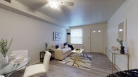 This single-floor residence offers a thoughtfully organized layout that maximizes comfort and functionality. The living room serves as the heart of the home, featuring light gray hardwood-style flooring, neutral-toned walls, and a ceiling fan that enhances both comfort and air circulation. A front door with glass panel accents allows natural light to filter in, complementing the window that brightens the space. The living area flows seamlessly into a dedicated dining space, which comfortably accommodates a round glass dining table with modern white chairs — ideal for casual meals or entertaining.

The galley-style kitchen is efficiently designed with white cabinetry, dark laminate countertops, and stainless steel appliances including a refrigerator, range, and sink, providing ample workspace for meal preparation.

The bedroom is a serene retreat, featuring the same warm flooring, a bright window with blinds for privacy, and a closet for storage. Framed artwork above the bed adds a touch of personality to the calm, neutral palette.

The bathroom is clean and functional, finished with white wall tiles and featuring a full-size soaking tub and shower combination. Throughout the residence, the consistent use of light tones and hardwood-style flooring creates a cohesive and welcoming atmosphere.