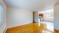 Located at 288 Woodbury Circle in Middletown, CT, this one-bedroom, one-bathroom unit offers a practical and well-organized single-floor layout. The living room is an open, airy space highlighted by gleaming hardwood floors that reflect natural light and lend warmth throughout. Neutral white walls keep the atmosphere clean and versatile, while baseboard heating ensures year-round comfort.

The kitchen is efficiently arranged in a galley style, featuring warm honey-toned wood cabinetry, gray laminate countertops, a white electric range, refrigerator, and dishwasher. Light vinyl flooring complements the cabinetry and ties the space together cohesively.

The bedroom is a comfortably sized retreat with the same polished hardwood flooring found in the living area. A wide window frames outdoor views of the surrounding neighborhood, allowing ample natural light to fill the room. Baseboard heating is also present here for consistent warmth.

The bathroom is finished with white square wall tiles, a wood-vanity with a white sink, a mirrored medicine cabinet, and a window that provides natural ventilation and light. The overall design of the unit is straightforward and functional, offering a clean, move-in-ready environment in a residential Middletown neighborhood.