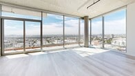 This striking 1,250 square foot apartment in Los Angeles offers a perfect blend of modern design and urban living. The space boasts four bedrooms and two bathrooms, with the primary bedroom spanning an impressive 270 square feet. Floor-to-ceiling windows dominate the living areas, providing breathtaking panoramic views of the city skyline and flooding the interior with natural light. The industrial-chic aesthetic is evident in the exposed concrete ceilings and visible ductwork, creating a loft-like atmosphere. Light wood flooring throughout adds warmth to the space, contrasting beautifully with the crisp white walls. The kitchen features sleek, light wood cabinetry, stainless steel appliances, and a central island, perfect for both cooking and entertaining. Bathrooms are designed with a minimalist approach, featuring large format tiles, floating vanities, and modern fixtures. The apartment's open floor plan and strategic layout maximize the use of space, while the large windows in each room ensure a bright and airy feel throughout. This property seamlessly combines functionality with style, offering a sophisticated urban retreat in the heart of Los Angeles.